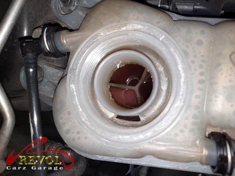 The old cracked coolant expansion tank removed from the engine bay.