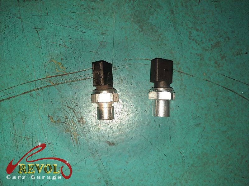 The old failed compressor and pressure switch removed alongside the new parts.