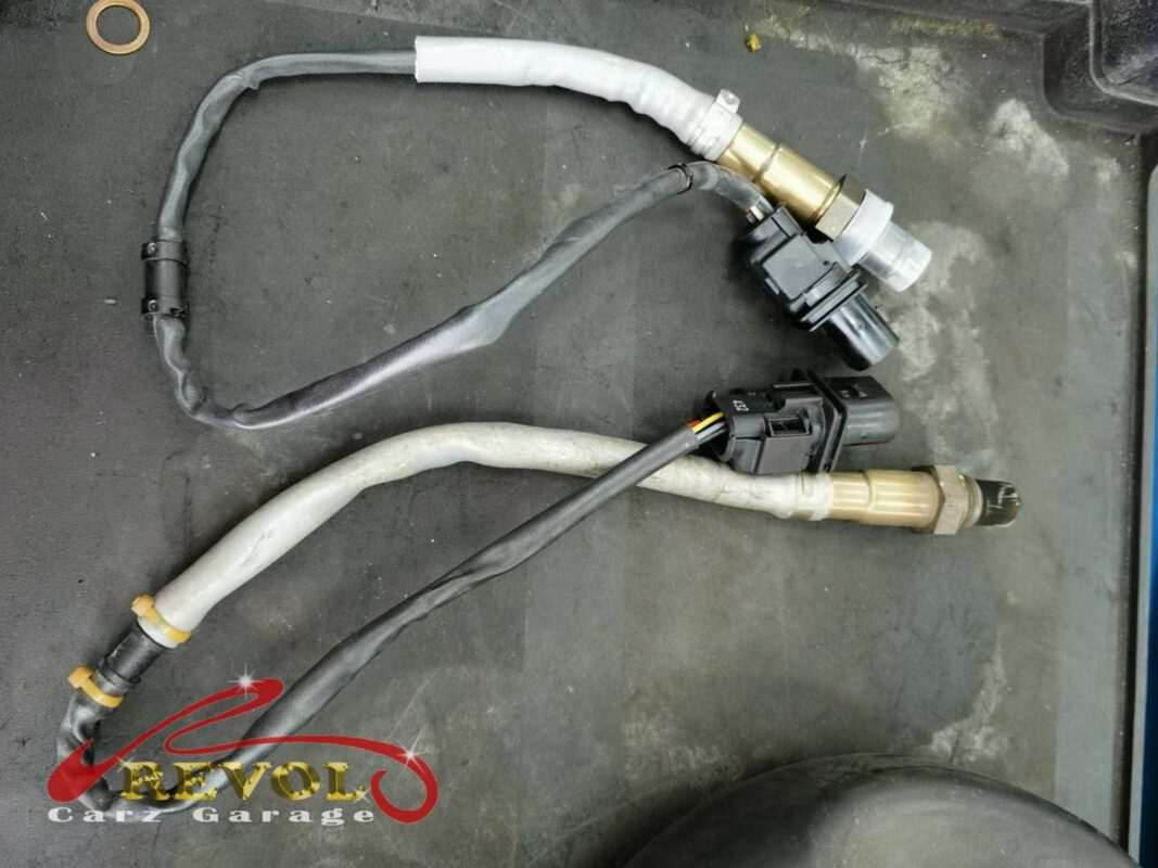 The old O2 sensor removed beside the new Audi-spec replacement.