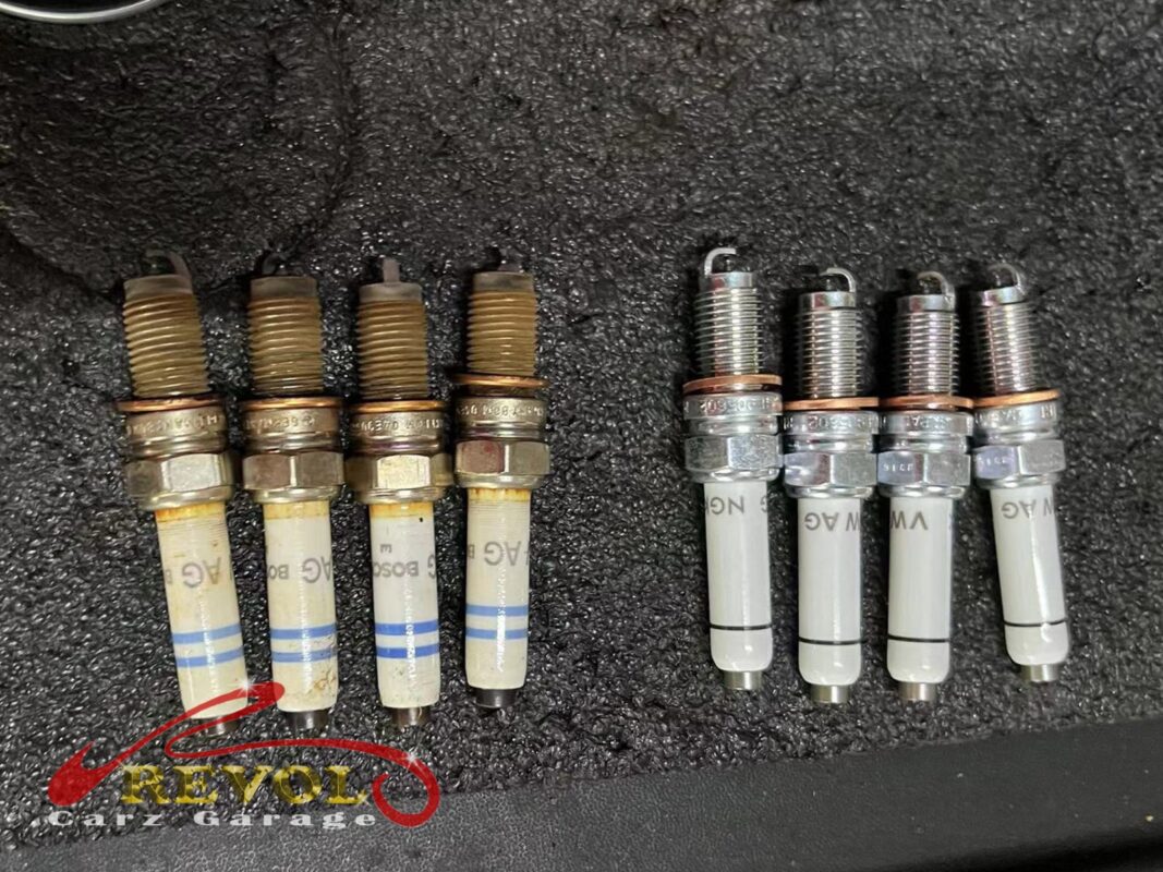 Old spark plugs across the engine, electrode wear past spec visible.