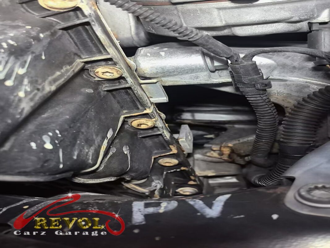 Inside the engine bay before work started. The whitish staining on the black plastic is dried coolant, the trail the leak had been leaving.