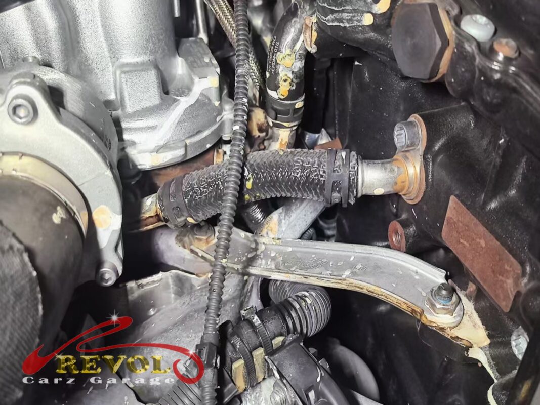 Crusty white residue across the hoses and pipework near the pump, where coolant had been seeping and drying over time.