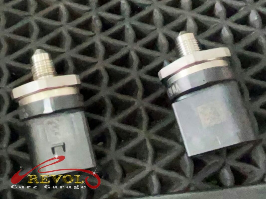 A pair of small engine sensors, old beside new, out for the swap.