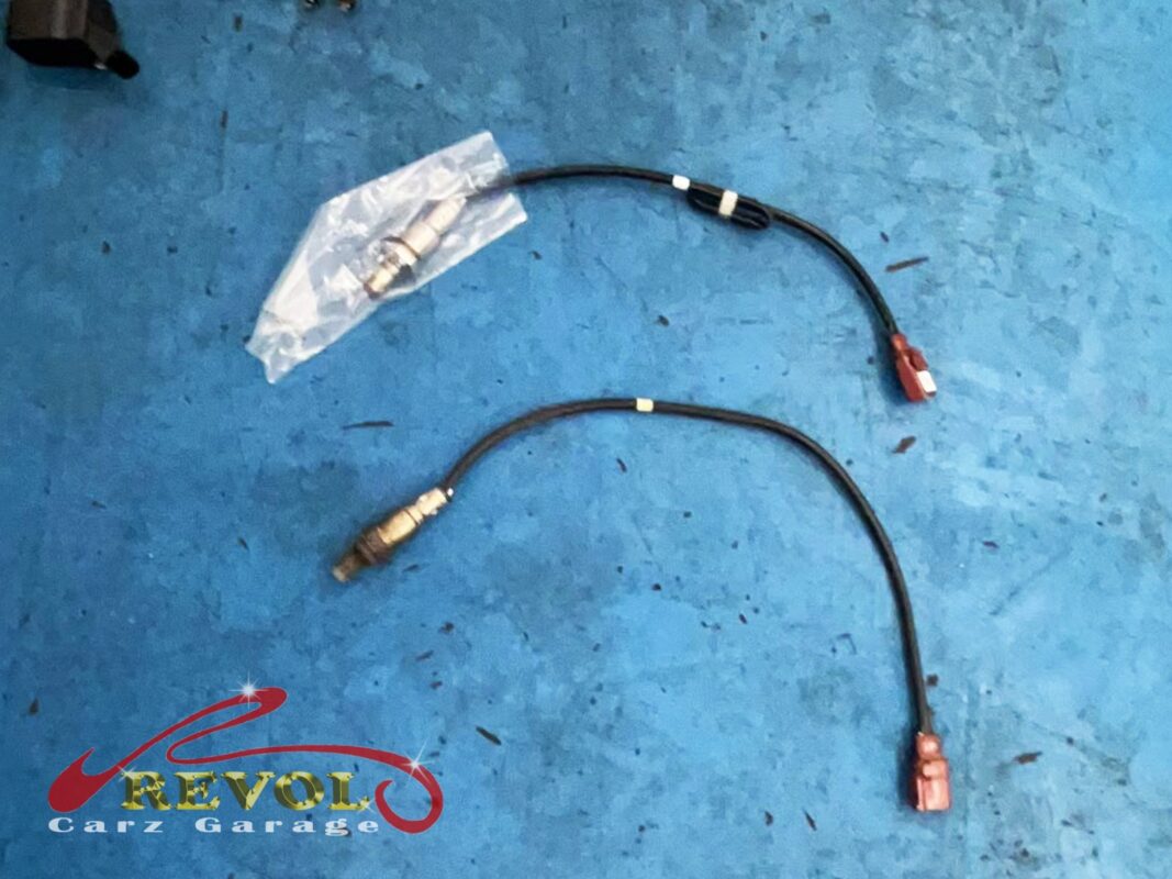 The old front oxygen sensor (bottom) next to its new VAG-spec replacement (top, still bagged with its long lead).