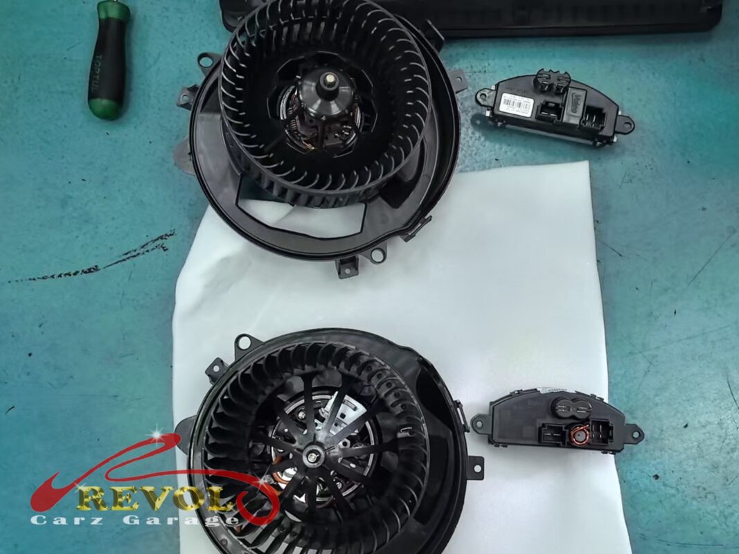 The old cabin blower motor (top) next to the new Audi-spec replacement (bottom), with the blower regulator module alongside.