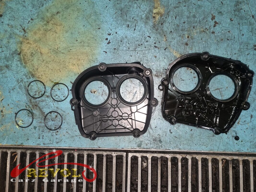 The timing cover pieces off the engine, laid out with fresh seal rings, ready to be cleaned back to bare metal and resealed.