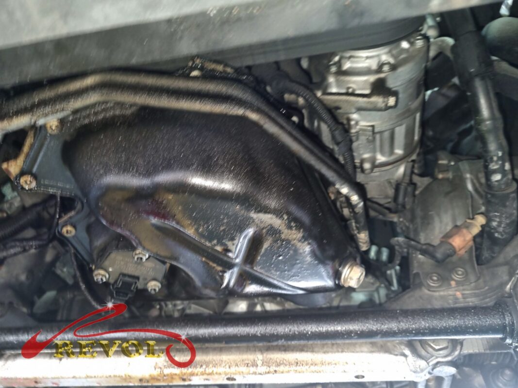 The oil sump area before the strip-down, the pan and the surrounding metal slick with weeping oil.