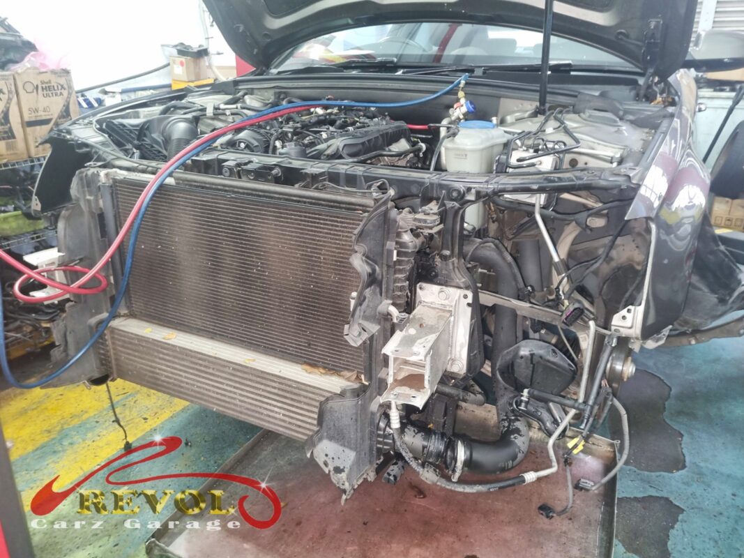 The front of the A4 with the bumper off, the condenser sitting ahead of the radiator and intercooler, AC service lines connected.