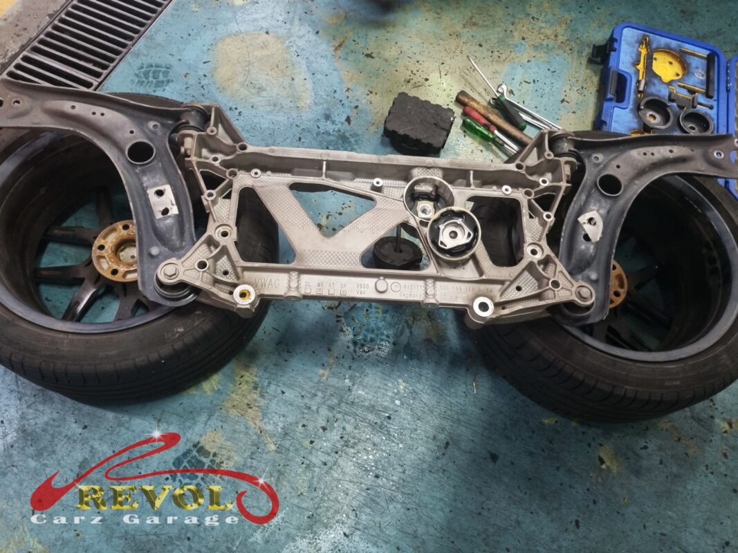 The front subframe dropped out of the car so the bushings could be pressed, with the press tool kit laid out alongside.