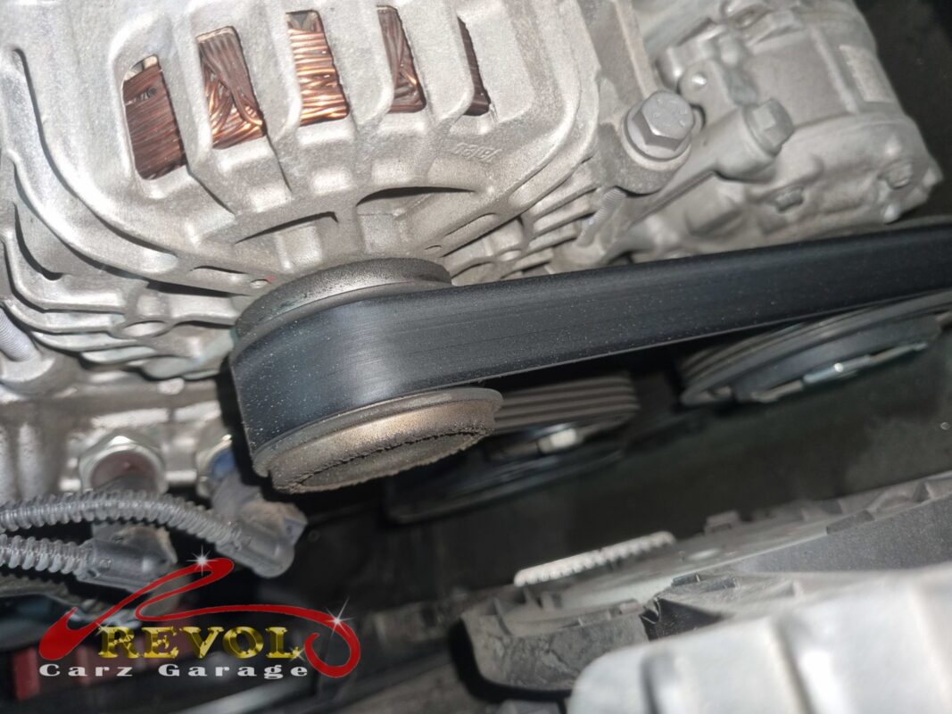 The auxiliary belt running over the tensioner pulley, with the alternator behind. The rib face had glazed and started to crack.