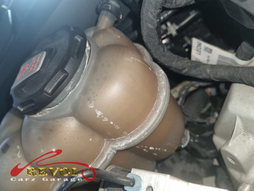 The coolant expansion tank in the engine bay, crusted with white coolant residue where it had been weeping.