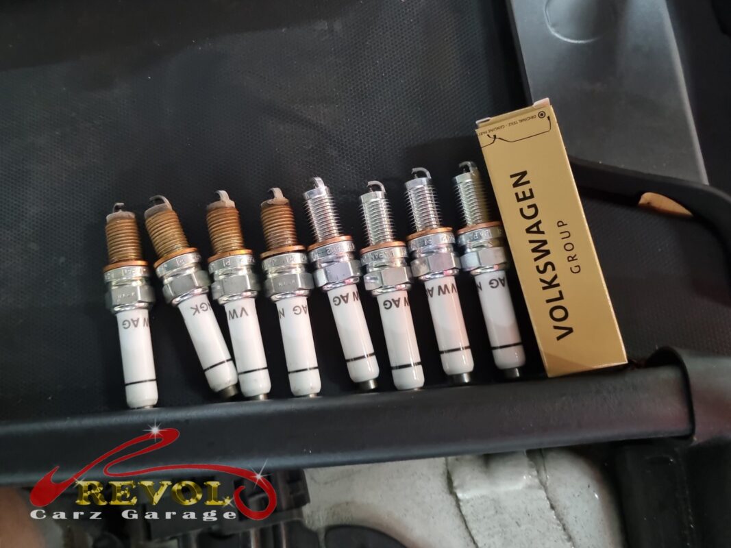 The four old spark plugs (left, rusted threads) next to four new VAG-spec replacements (right).