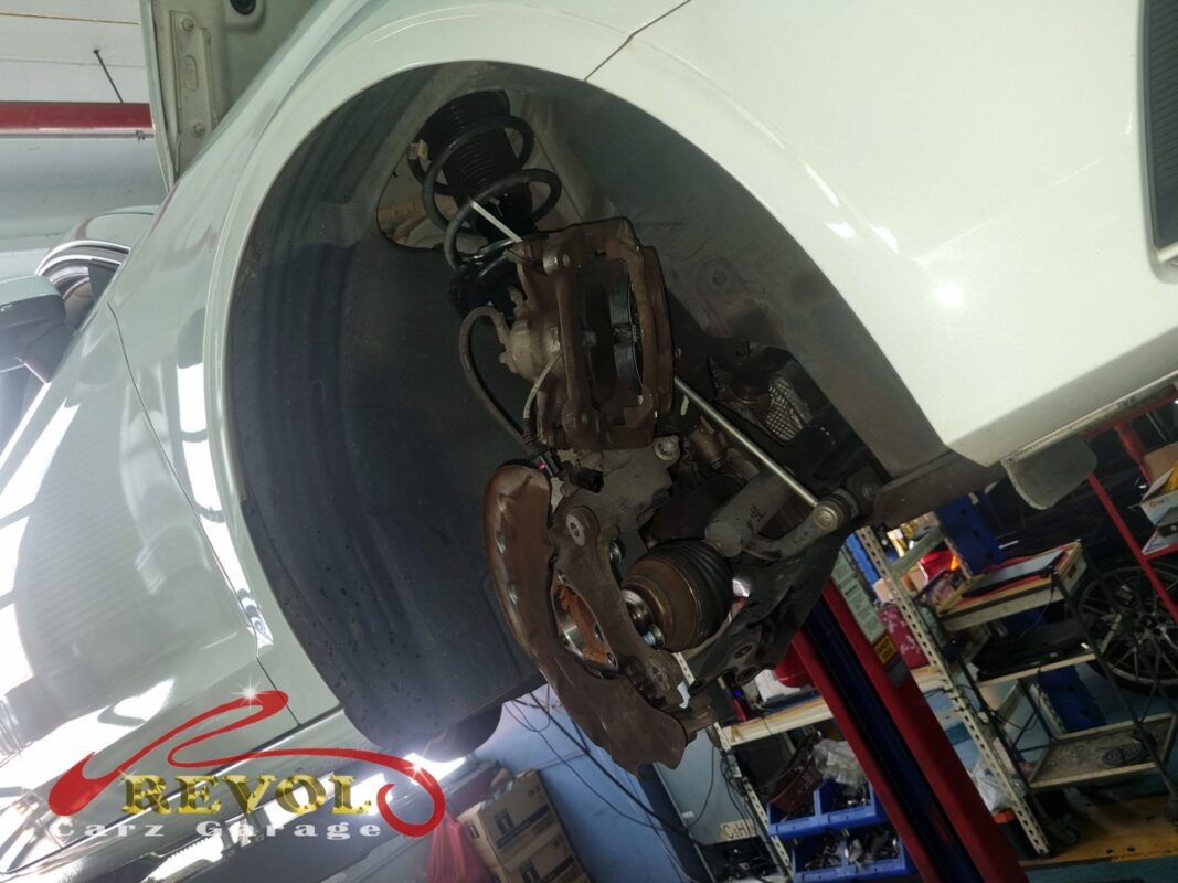 The rear hub area with the wheel off, brake disc, caliper and the suspension arms in view, where the noise was coming from.