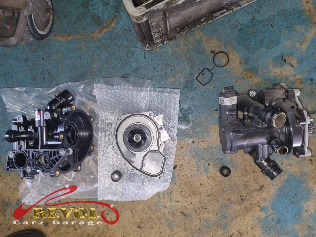 The new VAG-spec water pump module (left, still bagged, impeller alongside) next to the old one (right, grimy). Pump and thermostat housing in one unit on this engine.