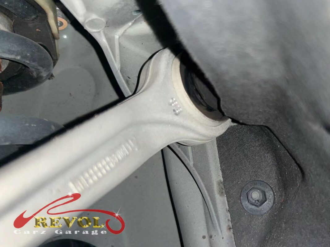 A close look at one of the front control arms, the bushing pry-tested to check how far the rubber gives.
