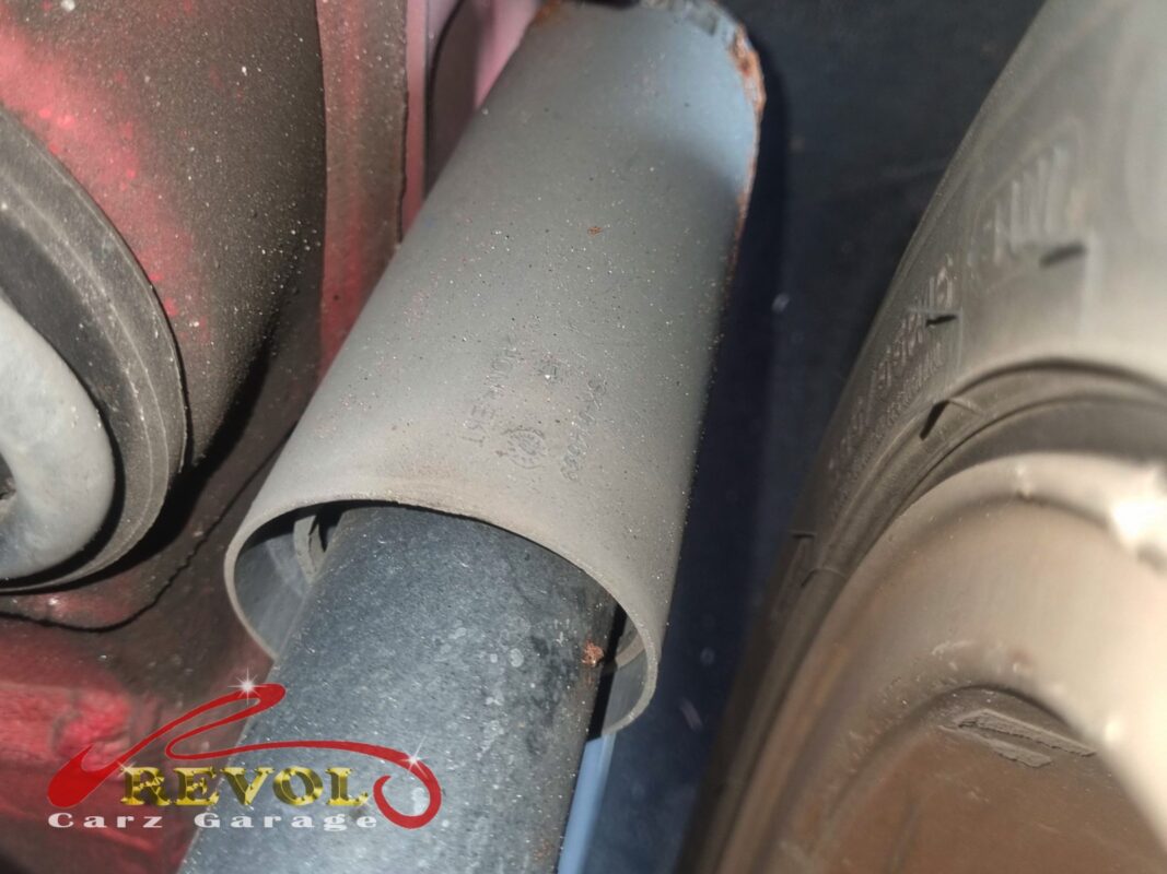 A rear shock absorber still on the car, the dust boot and the body showing the years on it.