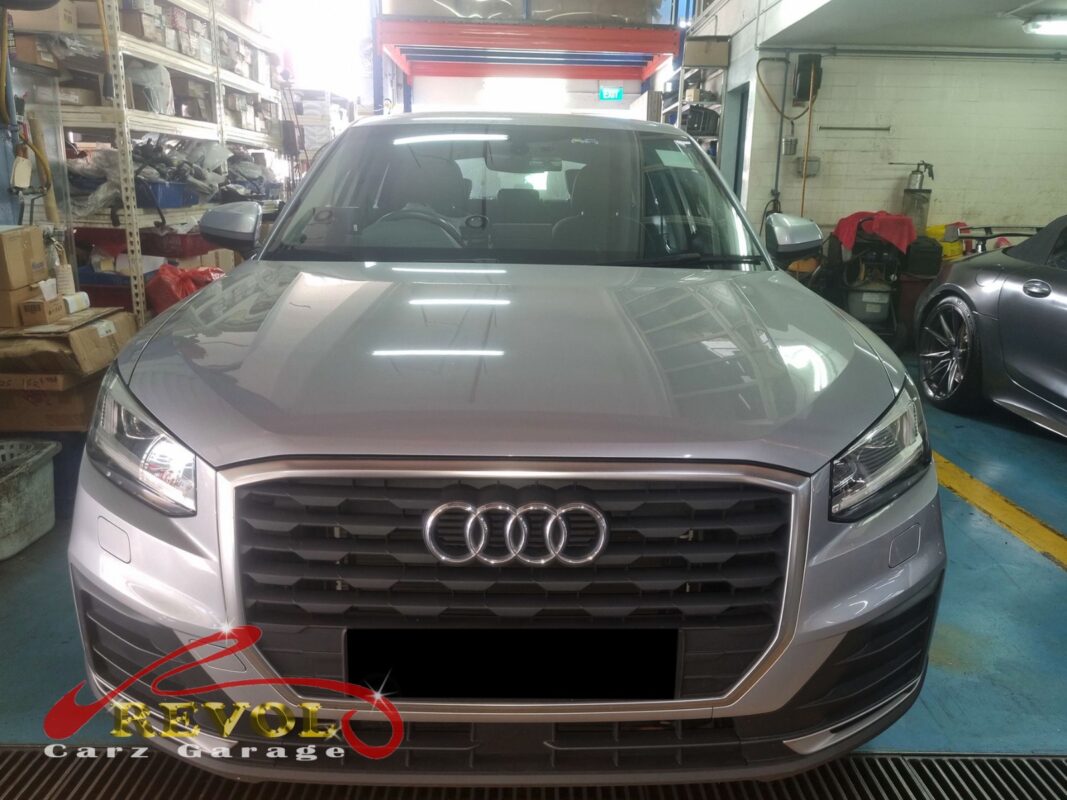 Audi Q2 on the workshop lift with front wheels off for brake pad and rotor inspection.