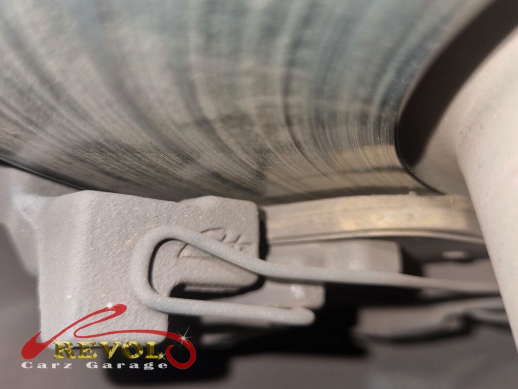 A front brake disc with the caliper bracket off, the face scored and a clear edge lip raised at the rim, well past its serviceable thickness.