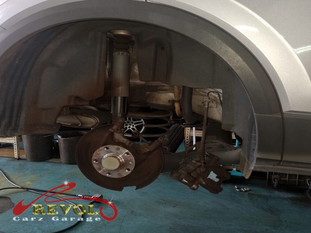 The front brake stripped, disc still on the hub and the caliper hanging clear, ready for the swap.