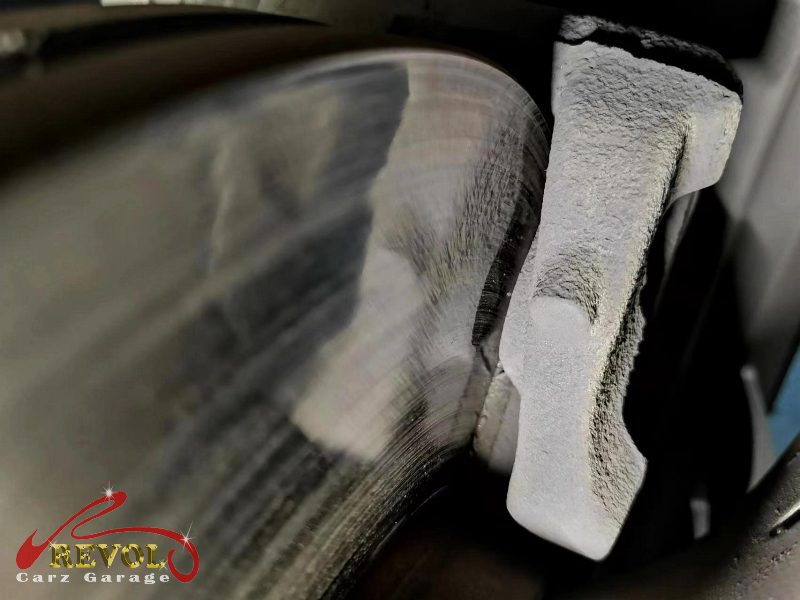 The worn front pads and heavily grooved disc on the BMW X1.