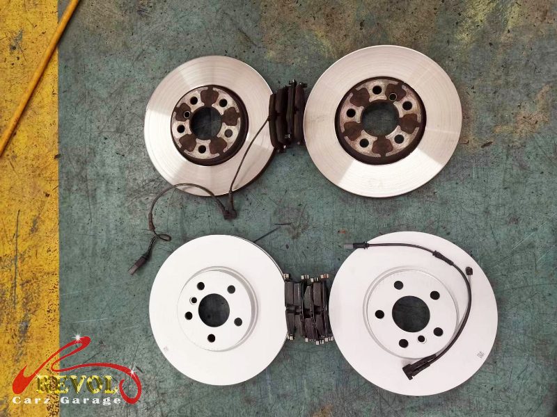 The old front discs removed alongside the new genuine set.