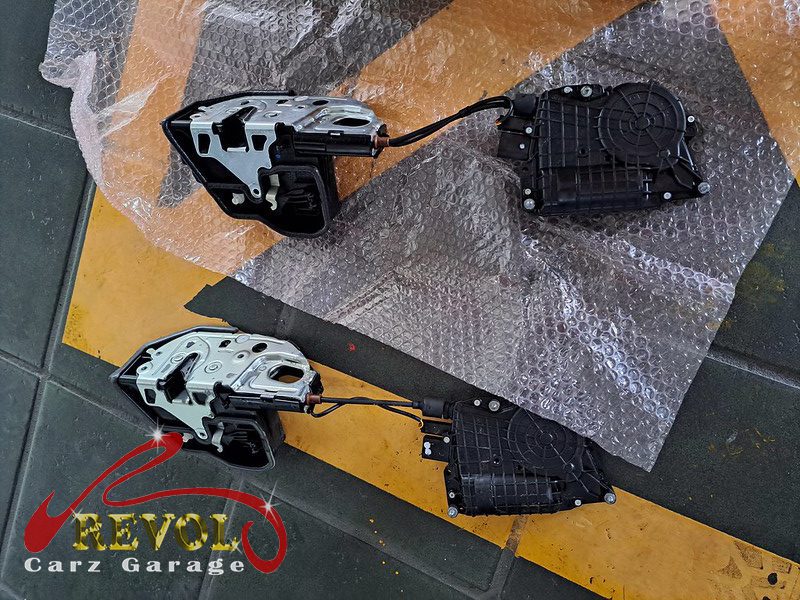 The door card off the BMW 760i showing the failed lock actuator, and the new unit fitted and tested.