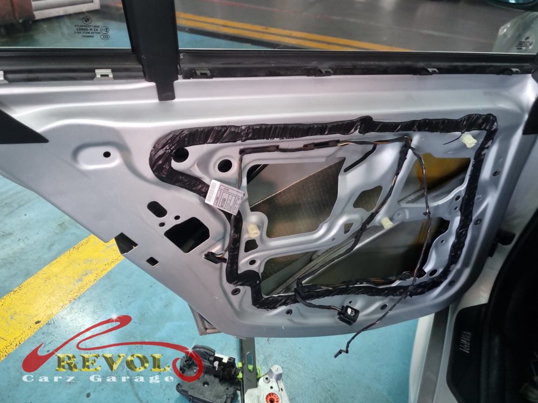 The door card off the BMW 325i showing the failed window regulator with frayed cable.