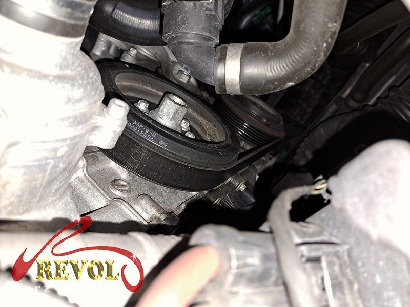 The old tensioner and idler pulleys removed alongside the belt.
