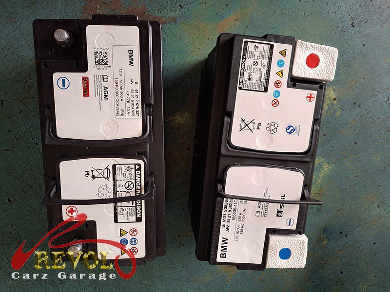 The old battery removed beside the new genuine BMW battery on the 318i, ready for IBS coding.