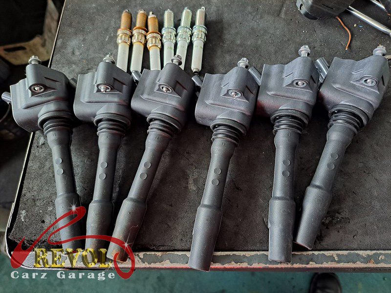 The old worn spark plugs beside the new BMW-spec plugs and ignition coils.