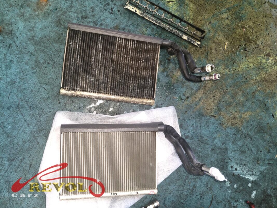 The old evaporator cooling coil removed beside the new BMW-spec replacement.