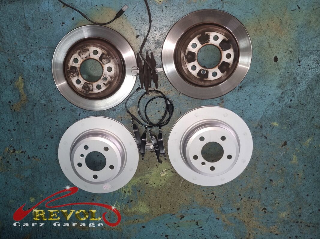 The two old brake discs with their worn pads (top) next to the two new BMW-spec discs and fresh pads (bottom), the brake inspection turning up work to do.