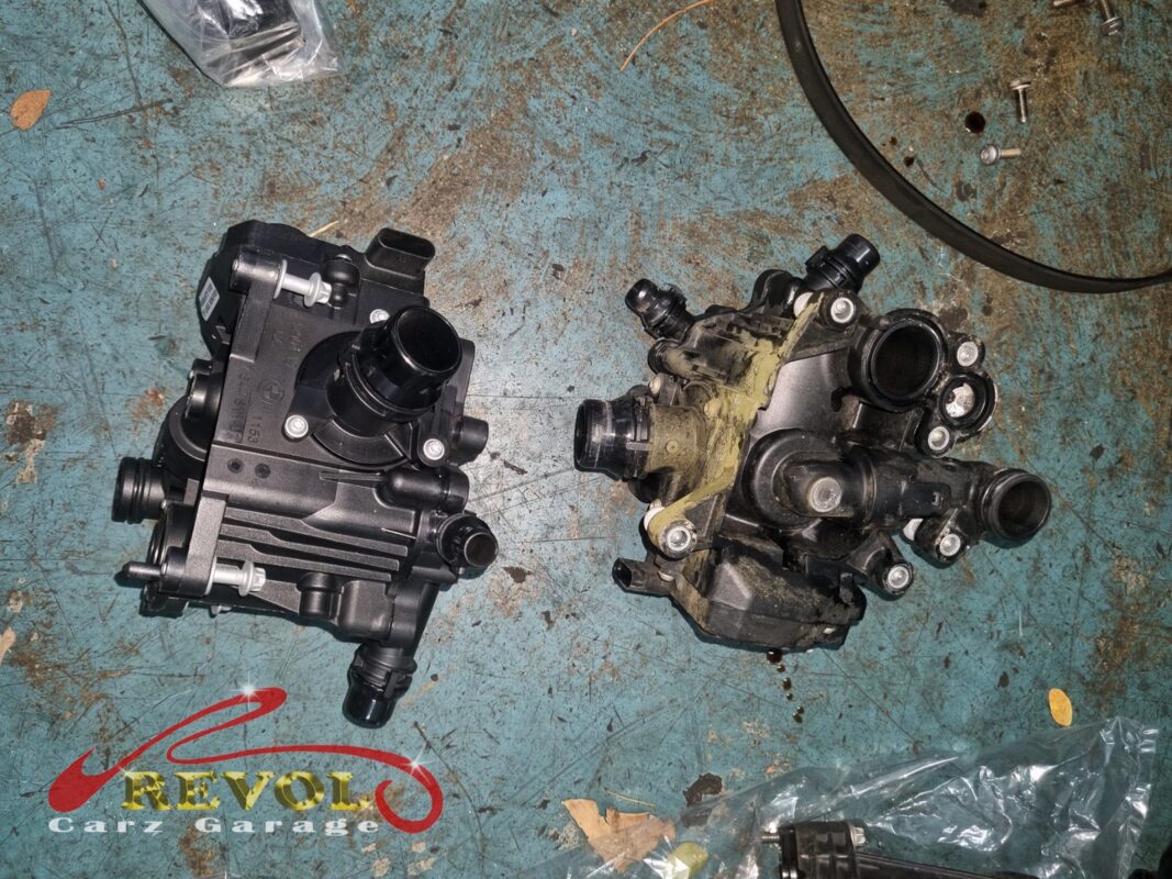 The new BMW-spec thermostat housing assembly (left) next to the old one (right, crusted with dried coolant residue).