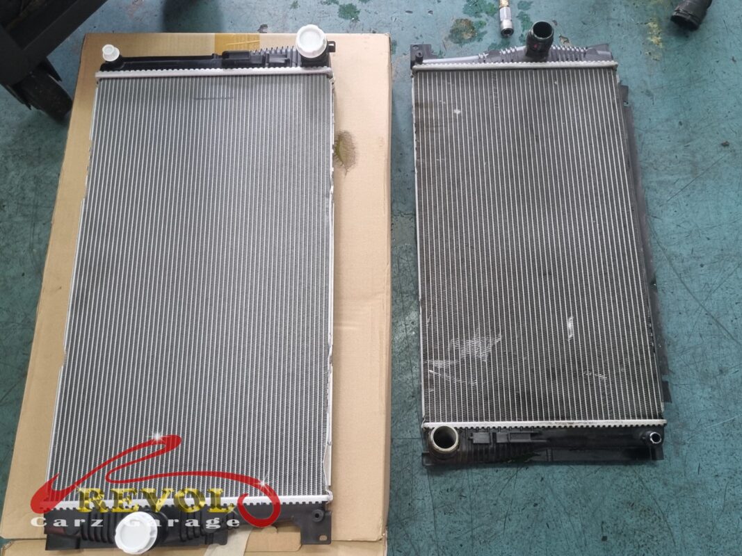 The new BMW-spec radiator (left, still on its packaging) next to the old one (right, oxidised and grimy).