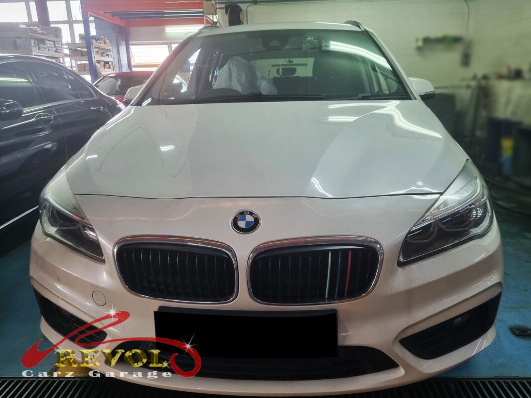 BMW 216i with the engine bay open for timing cover replacement.