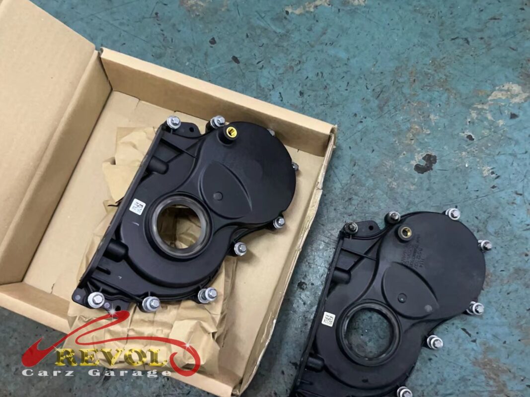 The new BMW-spec timing cover (left, in its box) next to the old one (right), with fresh seals ready to go on.