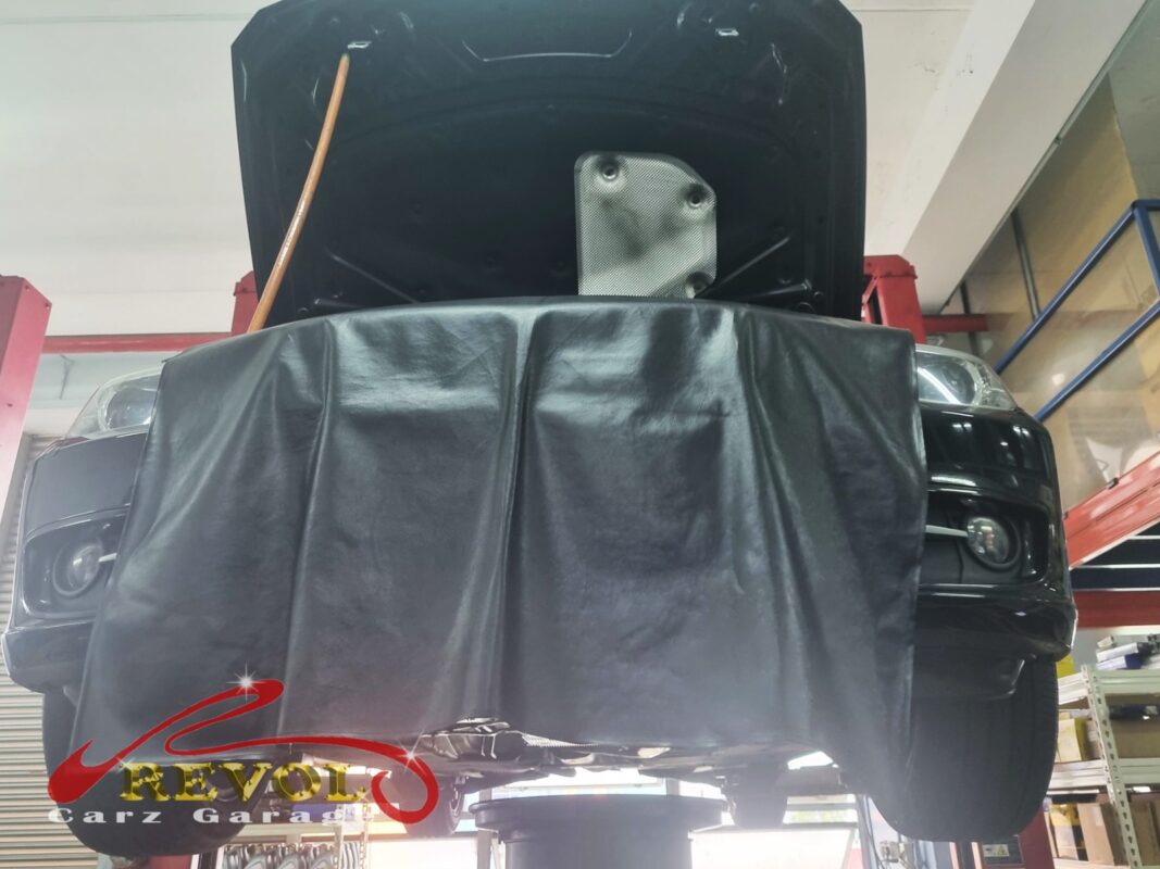 The BMW 316i up on the two-post lift, fender cover on, in for the engine mount work.