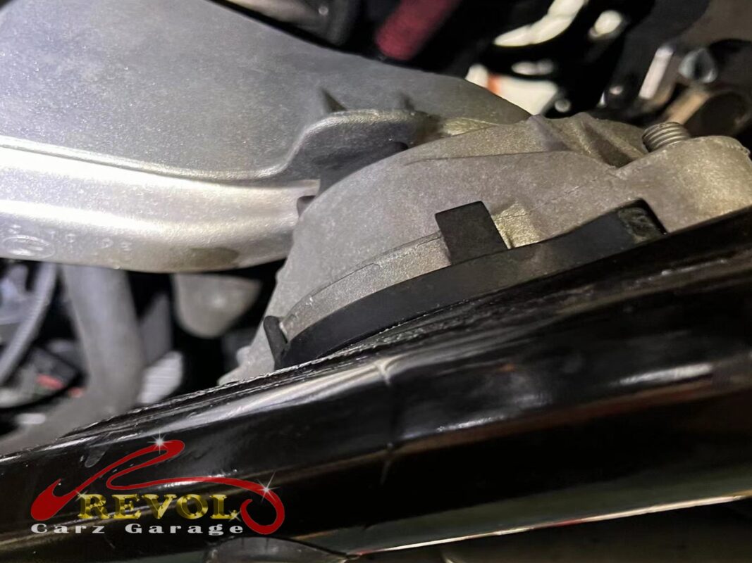 An engine mount in place on the car, pry-tested to check how much the rubber gives under load.
