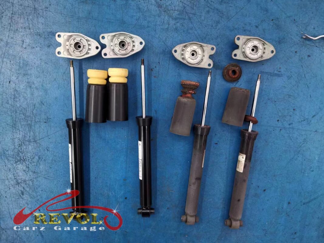 The old rear shocks and mounts (right) next to the new BMW-spec pair (left), with fresh bump stops, boots and top mounts.