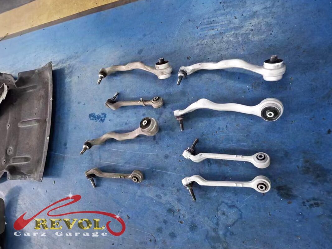 The front control arms laid out, the worn set out and the new BMW-spec replacements ready to fit.
