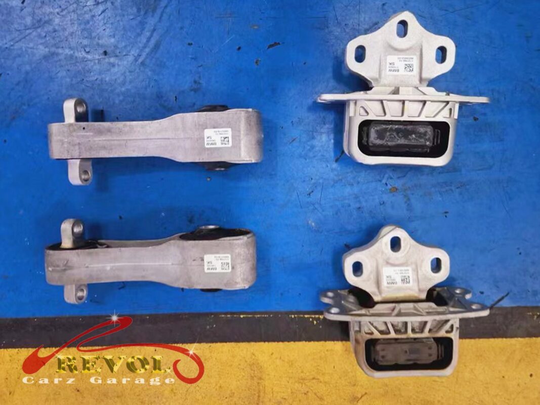The mounting set laid out, the worn pieces beside the new BMW-spec replacements: the torque-strut arms and the hydraulic mounts.