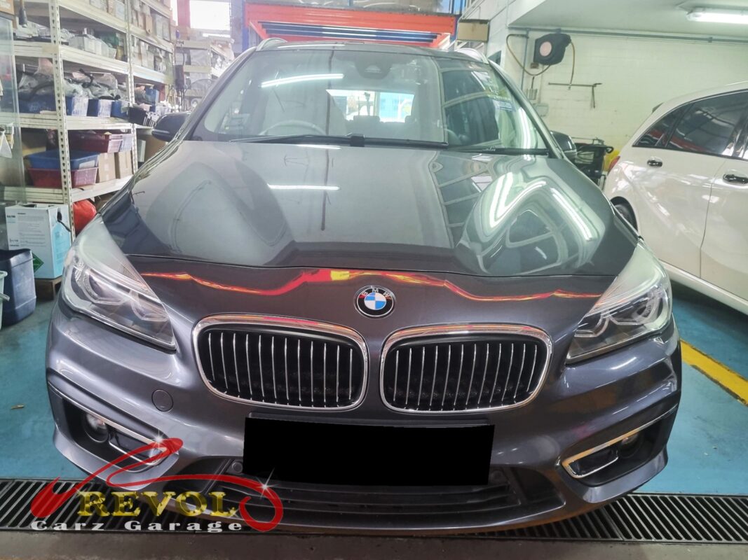 BMW 216d on the workshop lift with both front wheels off for control arm replacement.