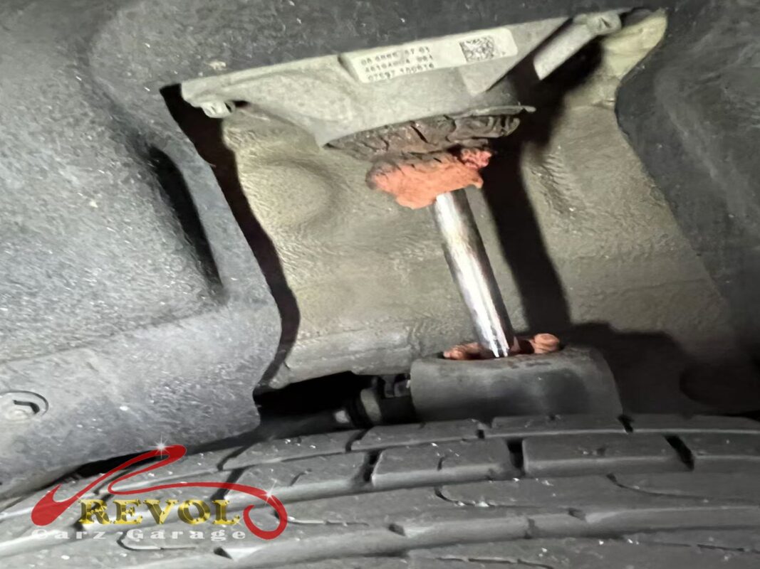 The top of one rear strut, dried oil and rust caked around the seal where the damper has been weeping.