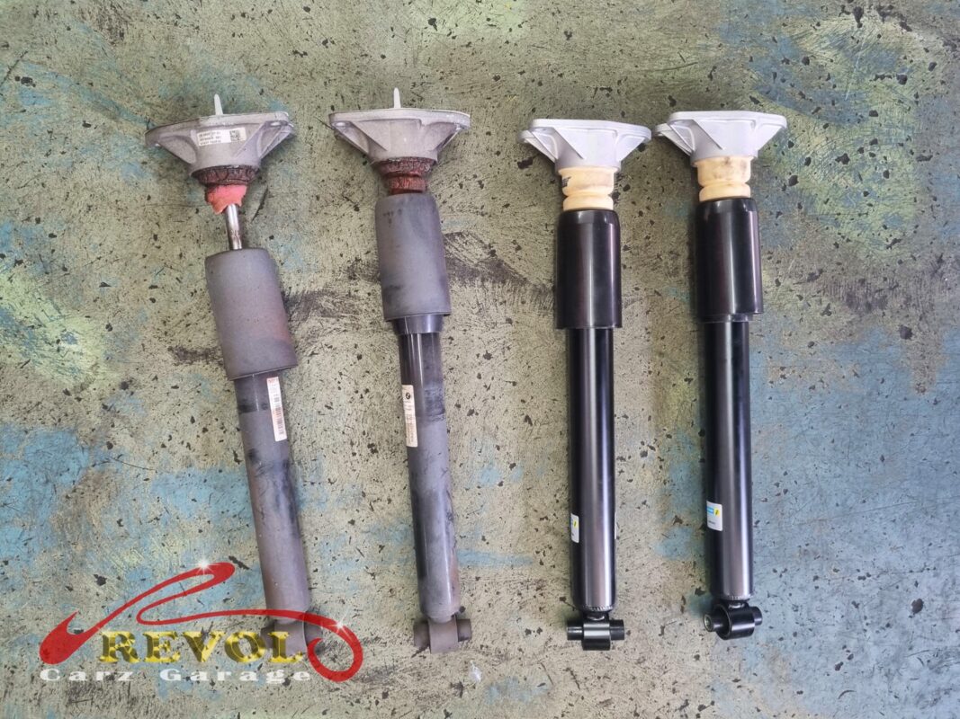 The two old rear shocks (left), worn and leaking, beside the new BMW-spec replacements (right).
