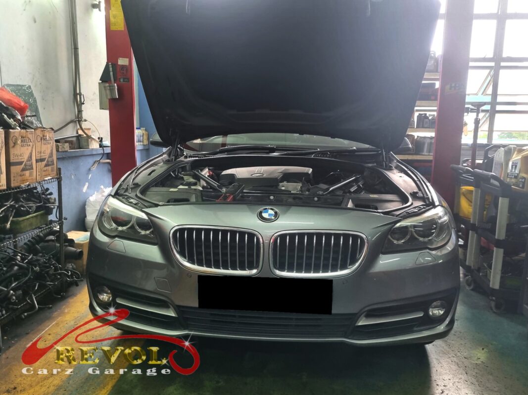 BMW 528i on the workshop lift with the engine supported on a jack for mount replacement.