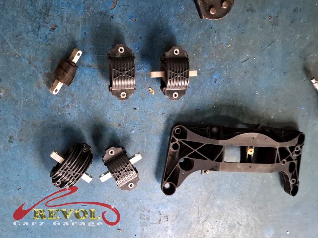 More of the mounting hardware: the gearbox mount and its plastic support bracket, old and new together.