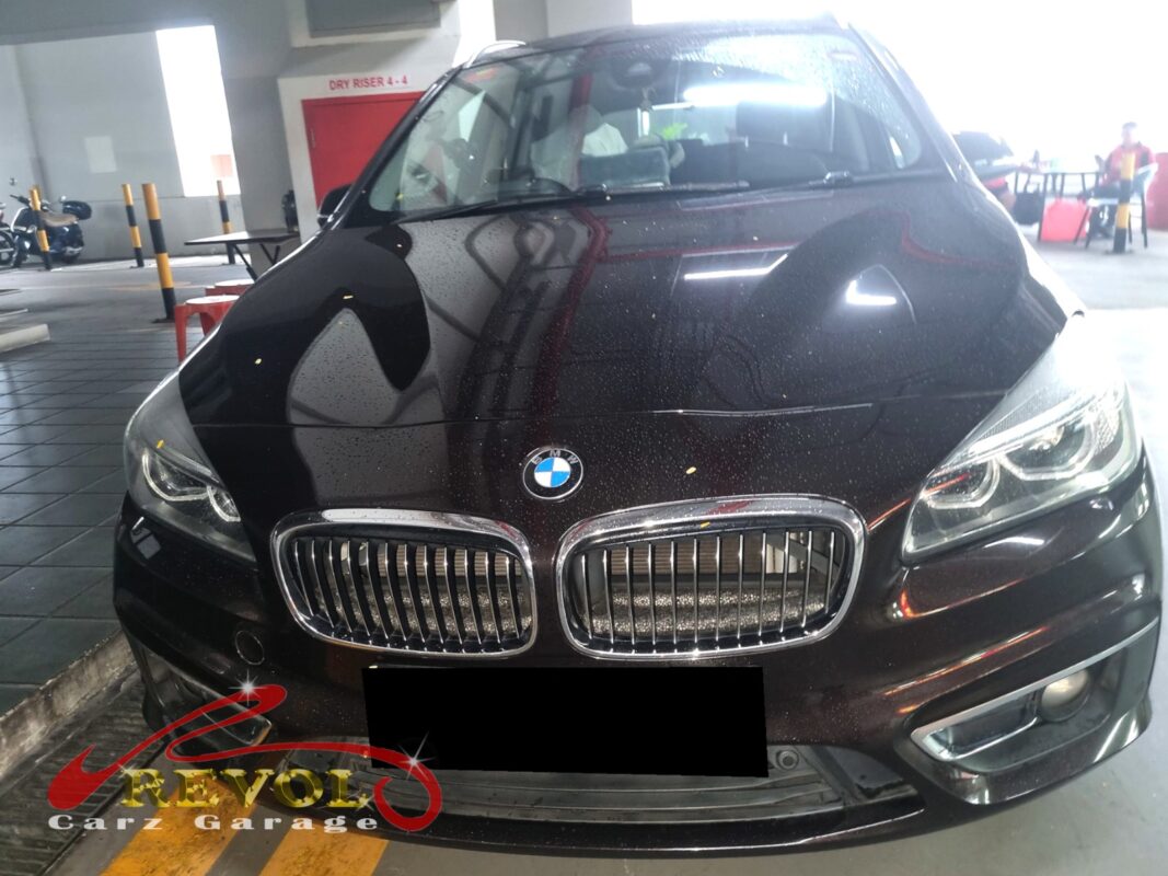 BMW 216d on the workshop lift with front wheels off for brake pad replacement.