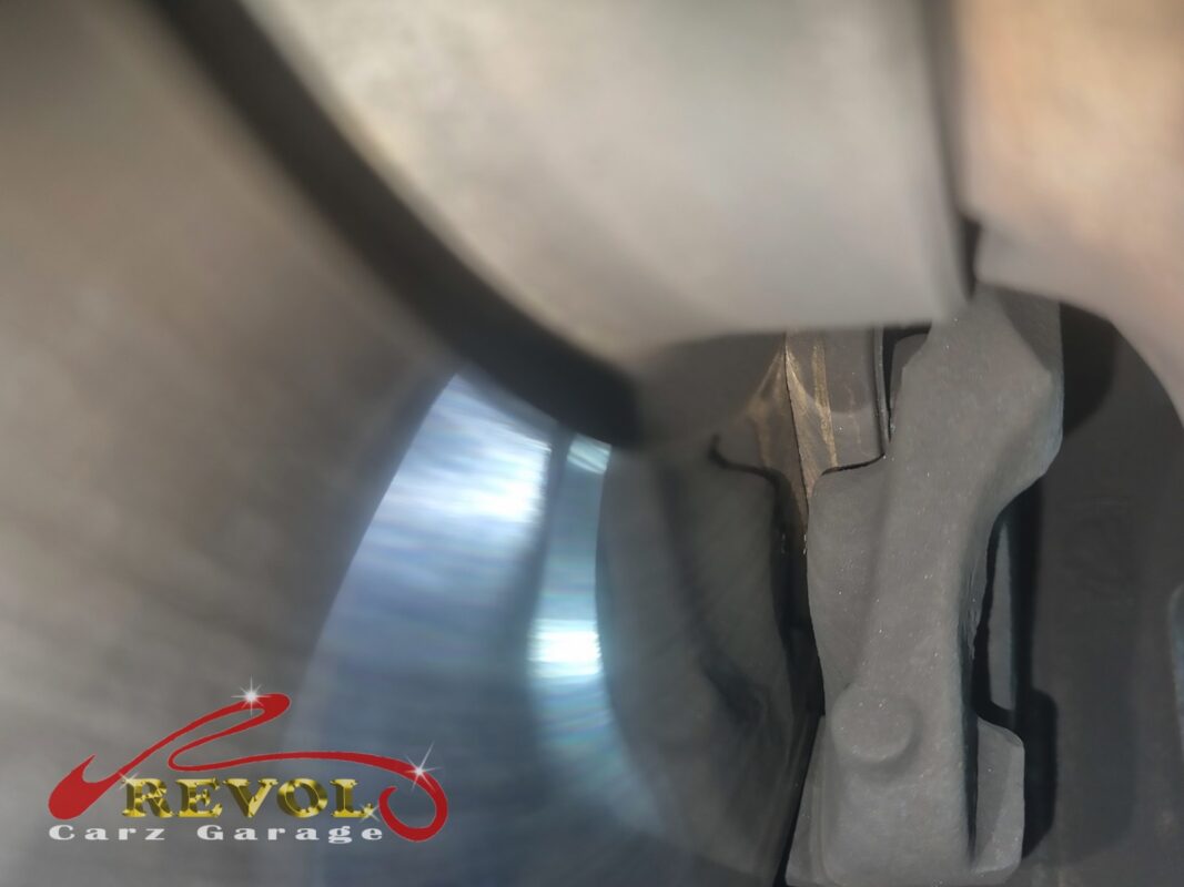 The worn front brake pad seen against the disc, the friction material down low.