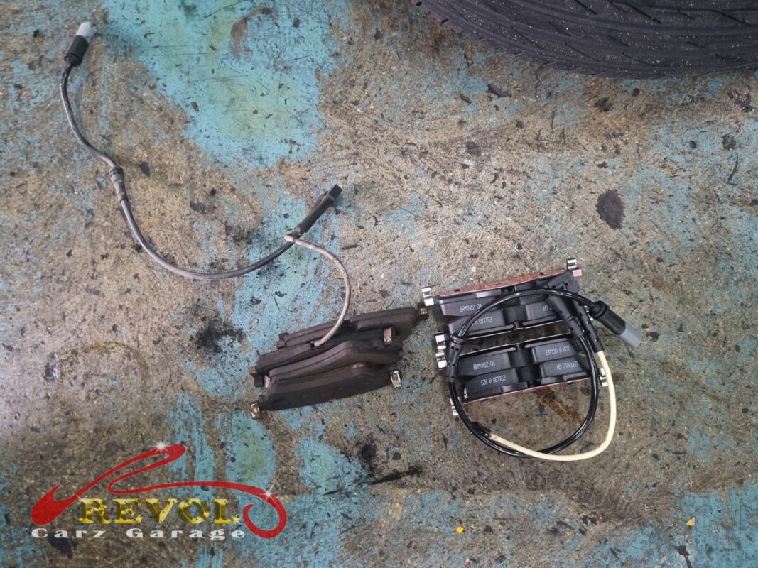 The worn front pads and sensor wire out (left), the new BMW-spec pads and fresh sensors ready (right).