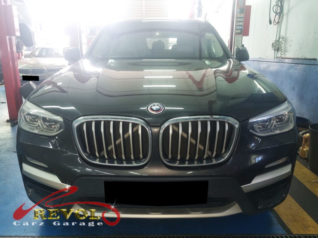 BMW X3 on the workshop lift with the engine bay open for water pump replacement.